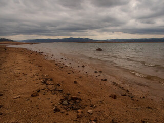 Shoreline of Folsom Lake CA really low water on dark cloudy day.