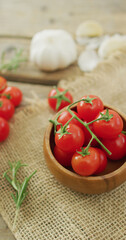 Vertical image of fresh ripe red cherry tomatoes and garlic on rustic cloth background