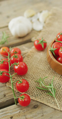 Vertical image of fresh ripe red cherry tomatoes and garlic on rustic cloth background