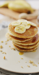 Fototapeta na wymiar Vertical image of stack of american style pancakes topped with banana slices