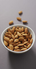 Vertical image of a bowl of almonds on a lilac background