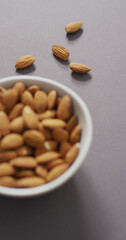 Vertical image of a bowl of almonds on a lilac background