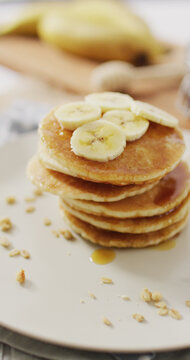 Vertical image of stack of american style pancakes topped with banana slices
