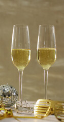 Vertical image of two glasses of champagne, mini disco ball and party glasses