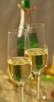 Vertical image of two glasses of champagne and open champagne bottle on table