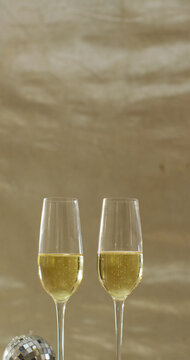 Vertical image of two glasses of champagne, mini disco ball and party glasses
