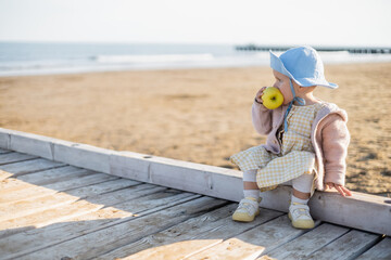 Side view of toddler child eating apple on wooden pier in Italy.