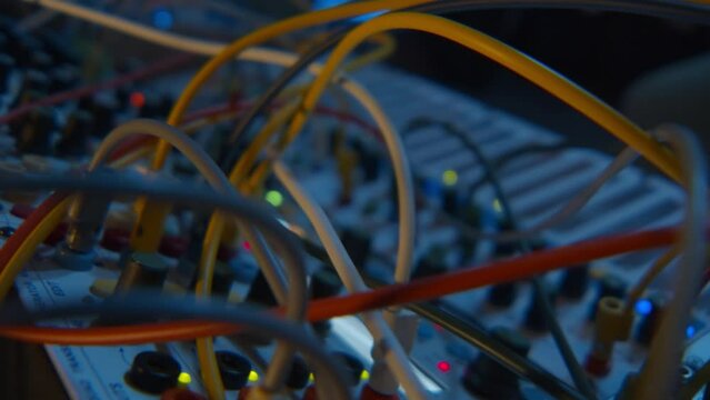 In a very close fixed plane, the camera focus travels through various synthesizers, going from the sequencer buttons to another synthesizer further away and returns to the sequencer when the beat pass