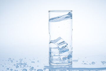 Ice cube fell into the glass of water. Water splashed from the clear glass. Fresh concept
