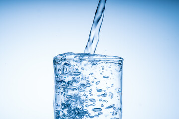 Ice cube fell into the glass of water. Water splashed from the clear glass. Fresh concept