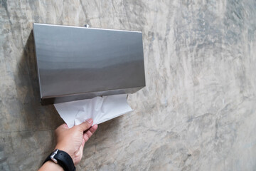 Man's hand pulling tissue to wipe his hands after using the toilet
