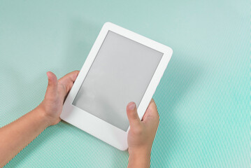 Ebook reader over green background - being held by the hand of a child