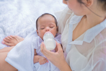 baby consumes milk from  bottle fed by mother