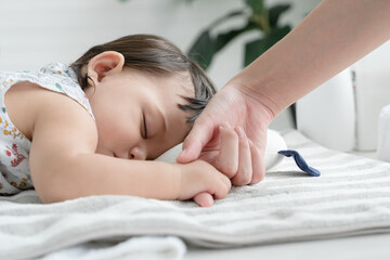 Adorable mixed race, Caucasian and Asian, little baby girl is sleeping and holding mother's finger...