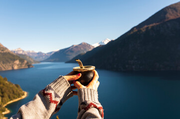 Young woman enjoying some delicious classic mates from Argentina in Patagonia. - obrazy, fototapety, plakaty