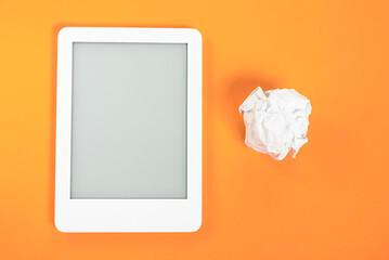 Ebook reader over yellow background with paper ball beside