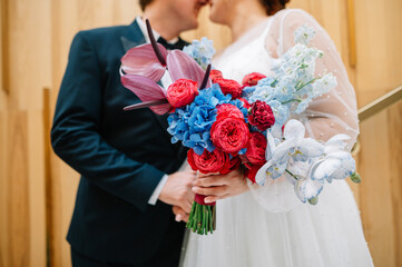 the bride and groom on their wedding day, kiss and hold a bright bouquet in their hands. No face photo