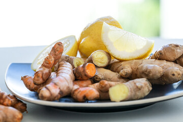 Roots of ginger and turmeric with lemon on plate