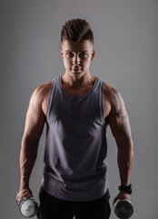 Fototapeta premium Handsome sporty young athletic man with shorty in sportswear with metal dumbbells on a dark background. Healthy lifestyle and workout