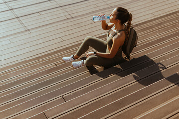 Pretty young woman takes a break after running in urban area