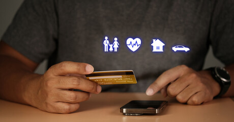 Man holding credit card and using smartphone at home office, Health Insurance and insurance Concept