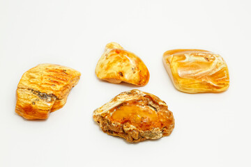 Four pieces of yellow amber on a white background. Natural patterns on fossilized resin. Copal. natural mineral. Jewelry material. Sun stone. Semi-precious crystal. Inclusions in amber