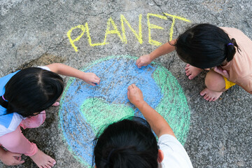 Volunteer family paints a beautiful world with the message Planet on asphalt. Little children and...