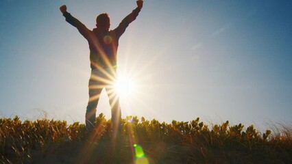Man stands on the grass and enjoys sunset