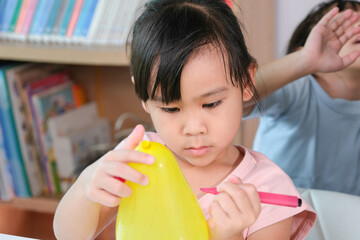 Little girl is learning and doing electrostatic science experiments with balloons in the classroom....