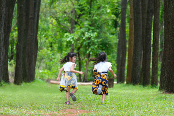 Happy children playing on the green grass in the spring garden. Two little sisters are running on a meadow in a summer park.