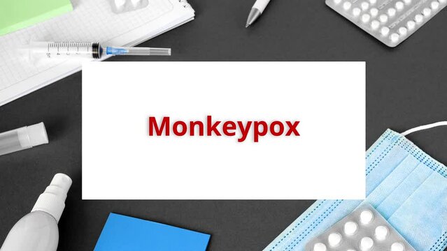 he word Monkeypox VIRUS on Gray modern doctor desk table background. Mask, notepad, syringe, blue gloves and supplies. Monkey pox spreading. Medicine and healthcare, medical education. Top view