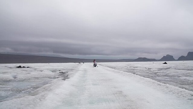 Aroup of tourists riding snowmobiles with a guide at Vatnajokull glacier in Iceland. Active sport, recreation, lifestyle.