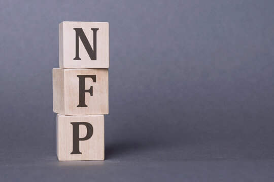 Word NFP - nonfarm payroll on wooden cubes with letters isolated on dark gray background,