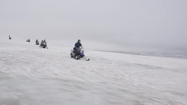 Aroup of tourists riding snowmobiles with a guide at Vatnajokull glacier in Iceland. Active sport, recreation, lifestyle.