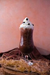 Creamy milk shake set in tall glass decorated with caramel and chocolate on colorful background. Front view.