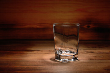 An empty glass stack, close-up on a wooden table and against the background of a wooden unfocused texture