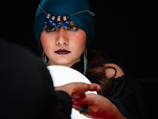 A mysterious magnificent beautiful woman fortune teller in a black dress holding a luminous crystal...