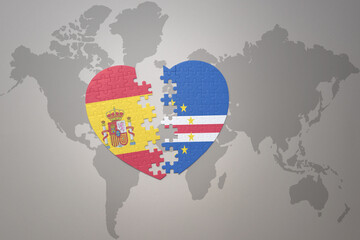 puzzle heart with the national flag of cape verde and spain on a world map background. Concept.