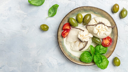 Italian burrata cheese with olives and cherry tomatoes, basil, olive oil on light background. Long banner format. top view