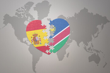 puzzle heart with the national flag of namibia and spain on a world map background. Concept.