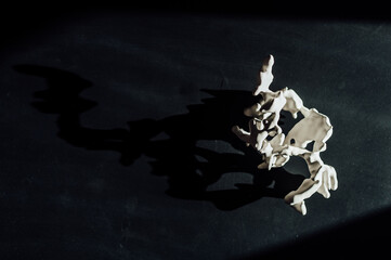 abstract white figurine in the shape of a coral on a black background in the rays of sunlight
