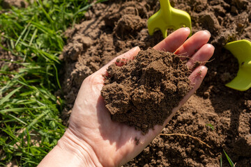 Close-up. A woman's hand holds a handful of earth. Spring, earth care