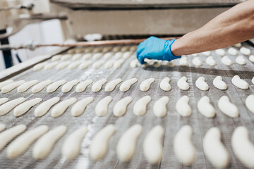 Huge factory line for sweet food and cookies production. Close up shots of worker's hand with protective glove doing some selection and product arranging.