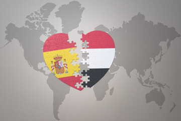 puzzle heart with the national flag of yemen and spain on a world map background. Concept.