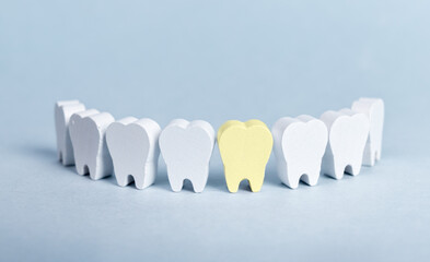 Teeth in smile form with yellow sick tooth with plaque on blue background. Cavity, decay...