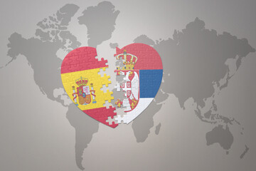 puzzle heart with the national flag of serbia and spain on a world map background. Concept.