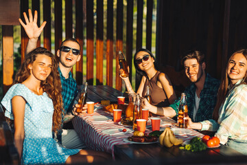 people have lunch and have fun together, drink drinks while sitting at a table in nature. friends eating barbecue