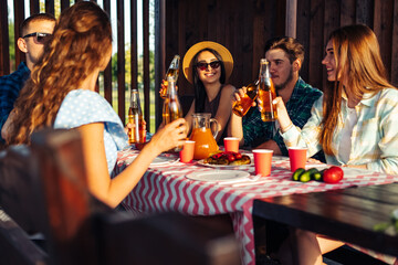 company of cheerful friends having fun at the table during a picnic gathered for barbecue. Friends have fun