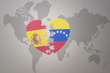 puzzle heart with the national flag of venezuela and spain on a world map background. Concept.