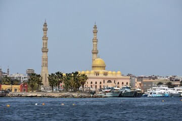 Fototapeta na wymiar View of the coastline with the Mosque El Mina Masjid, yachts and buildings, in New Marina in Hurghada, Egypt.